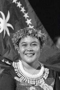 Woman in traditional wear in front of a flag